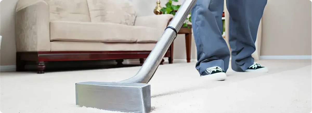 Carpet cleaning technician using a hot-water extraction wand on a light-colored carpet in a living room, Denver, CO.