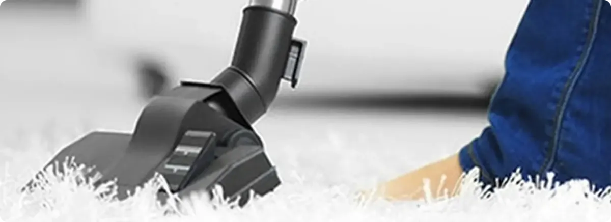 Close-up of a professional vacuuming a white carpet in Englewood.