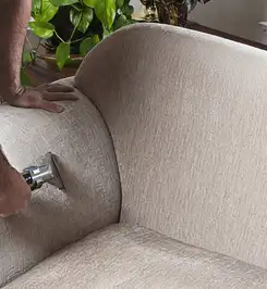Professional upholstery cleaner deep-cleaning a fabric sofa with a handheld extraction tool and hose Denver, CO.